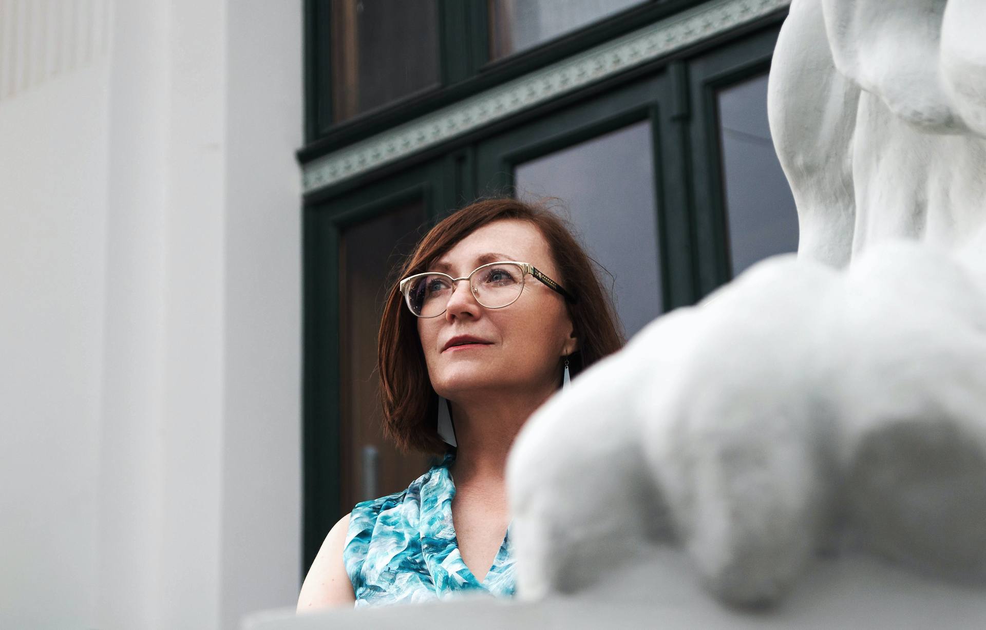 A close up on a woman wearing glasses outside a museum